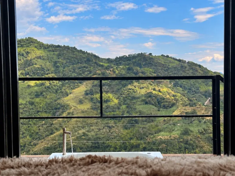 Cama king-size frente a los ventanales con vista al valle